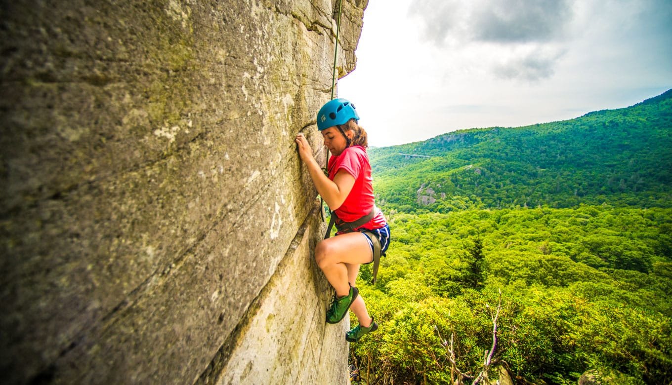 Girl climbing a smooth rock wall